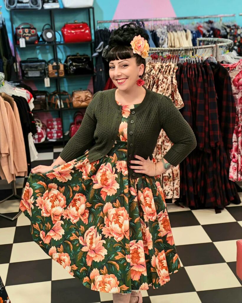 Femme portant une robe pin-up verte à grandes fleurs roses avec cardigan vert – Sweet Candy Shop